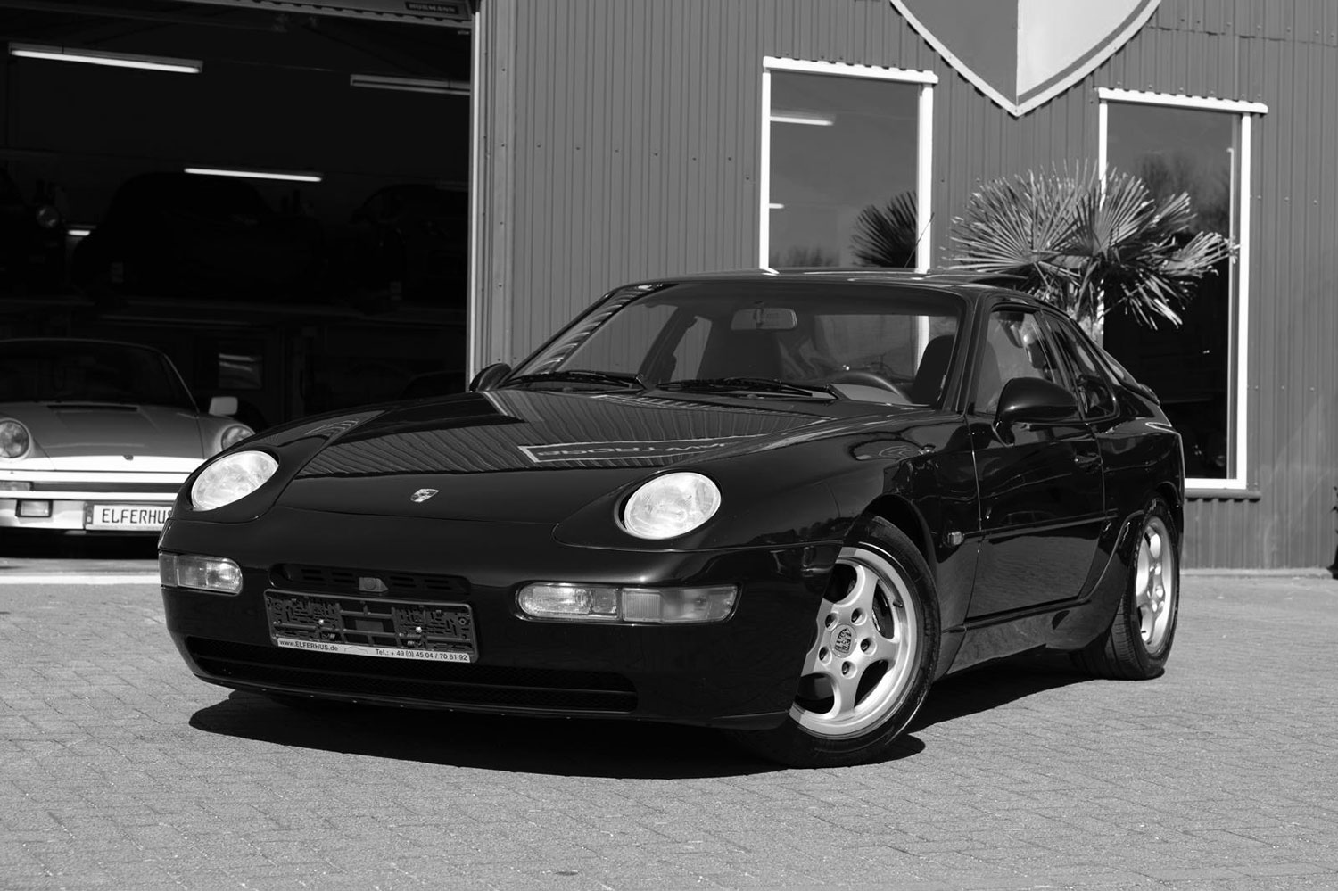 Schwarzweiss-Bild von einem Porsche 968 vor der Porsche Werkstatt in Ratekau. Dieser klassische Sportwagen wird von dem Porsche Spezialisten Elferhus angekauft.